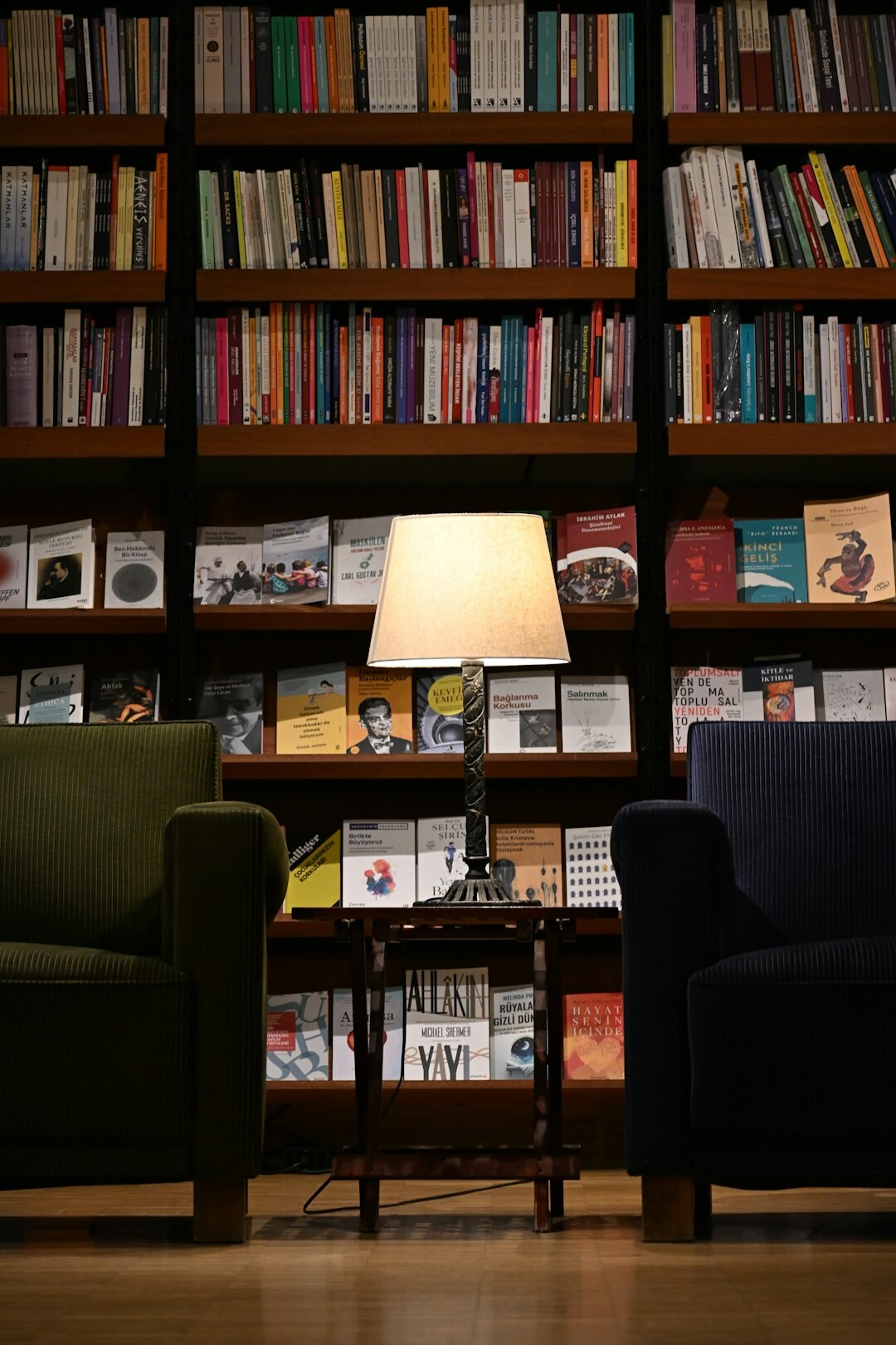 Cozy reading nook with an armchair, lamp and stacks of mystery books